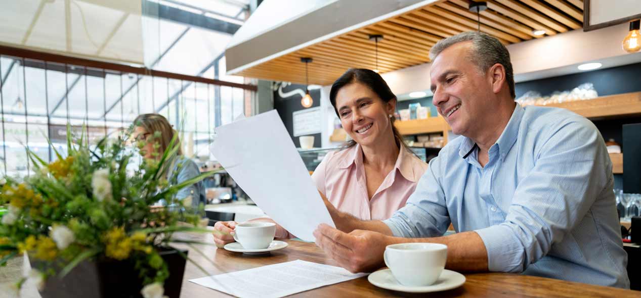 Couple looking at documents sitting at business